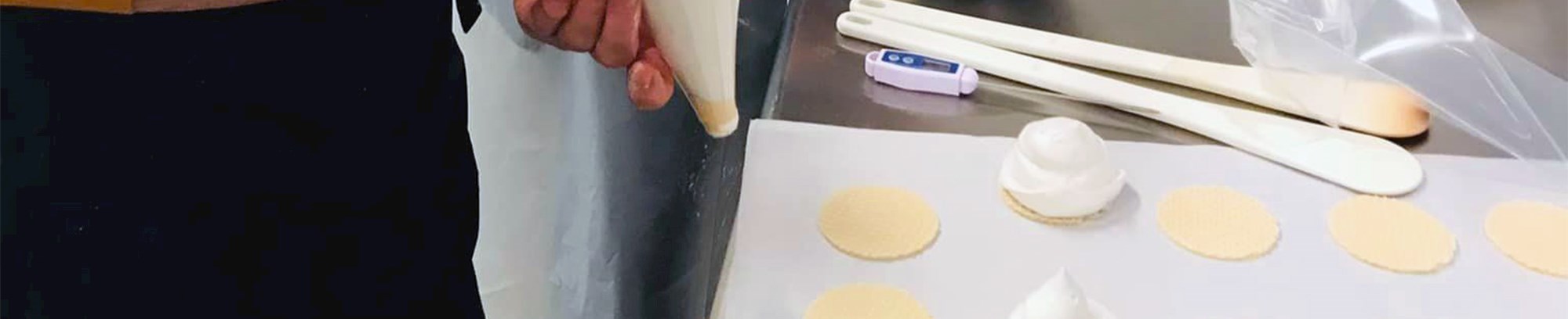 Kursister, der presser flødebolle-creme på makronbunde