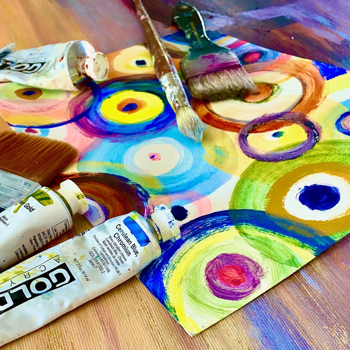 Akrylmalet billede med pensel og akrylmaling liggende oven på